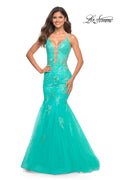 A woman smiles against a plain white background wearing the Aqua Blue Long Lace Prom Dress: La Femme 30675, featuring a mermaid silhouette and plunging neckline.