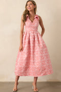 Pink coral dress with self-tie bow straps, a v-neckline, and a softly flared silhouette.