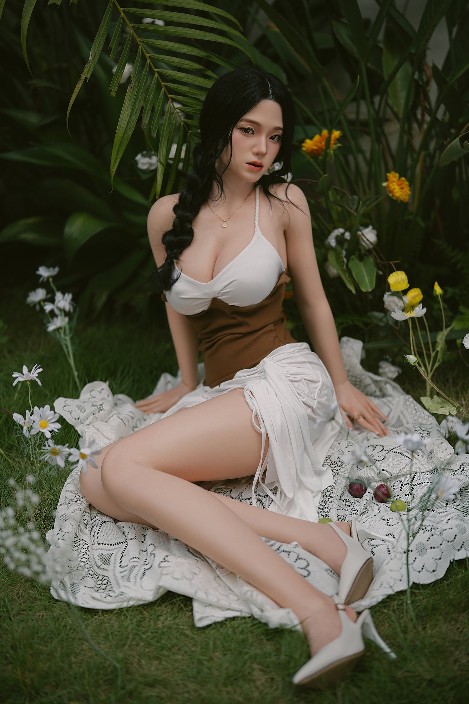 Full body view of a silicone sex doll with black braided hair wearing a white and brown outfit sitting in a garden