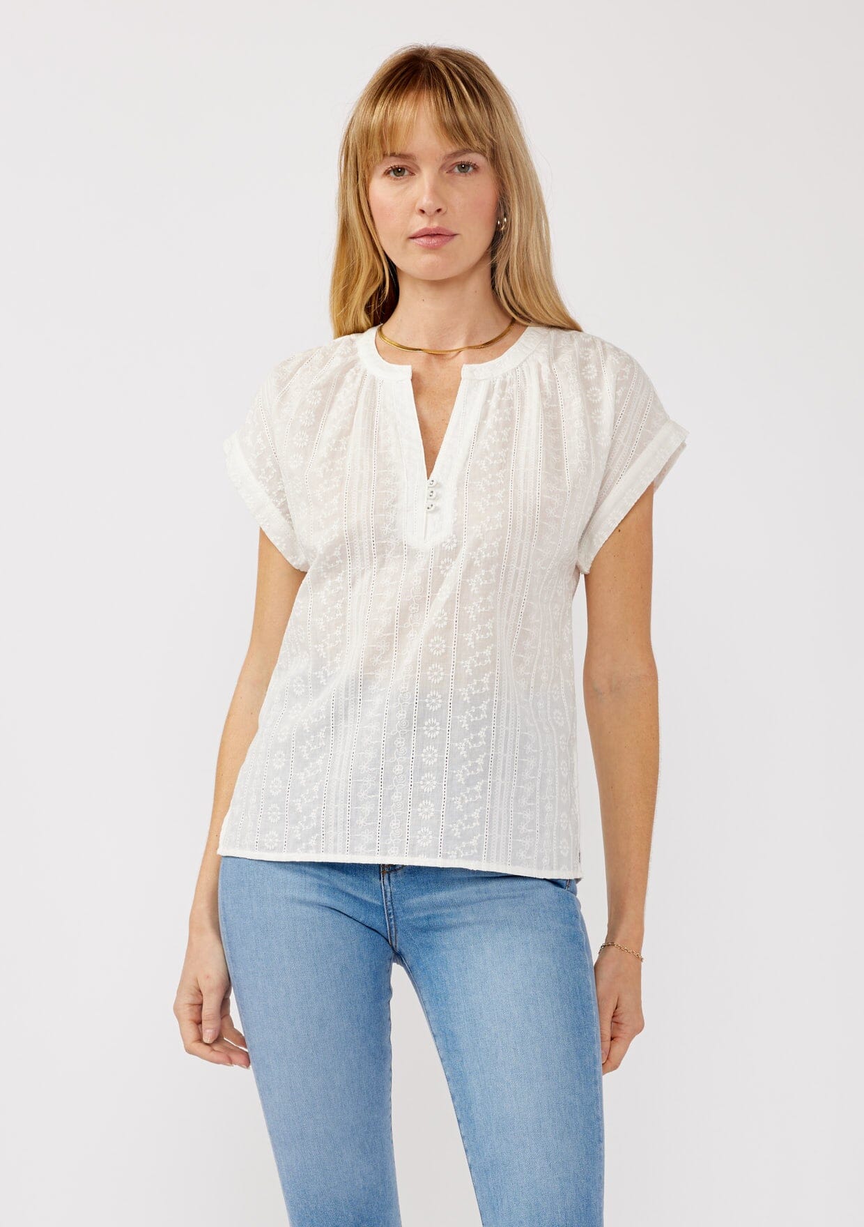 [Color: White] A front facing image of a blonde model wearing a white floral stripe embroidery with short dolman sleeves and a split -neckline. A lightweight cotton sheer top perfect for casual and resort styling.