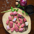 Kentucky grass-fed rose veal stew meat on wooden board with onion, mushrooms, peppercorns, and herbs