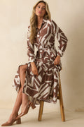 Maxi dress with brown and ivory abstract print, collared neckline, long sleeves with button cuffs, and flowing tiered skirt panels.