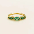 Juvetti yellow gold ring featuring lab-grown emeralds in oval, princess, and round cuts for a timeless half-eternity look.