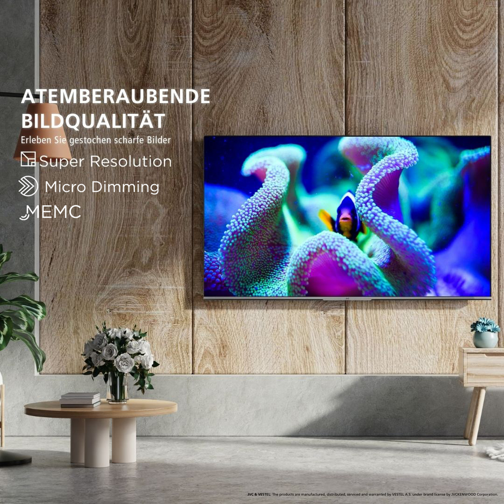 JVC 50" 4K UHD Smart TV mit Korallenbild, Clownfisch, Holzverkleidung und Dolby Vision auf Tisch mit Büchern und Vase.